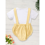 Flat lay of baby boy 2-piece first birthday romper set with white t-shirt and yellow safari suspender