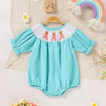 Green baby girl bunny romper set with bubble sleeves, white embroidered collar with pink bows, and bunny patterns on a light-colored lace background.
