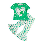 Green short sleeve girls t-shirt featuring a white heart and green clover print, paired with matching white flare leg pants covered in a shamrock clover pattern, displayed on a clean white background.